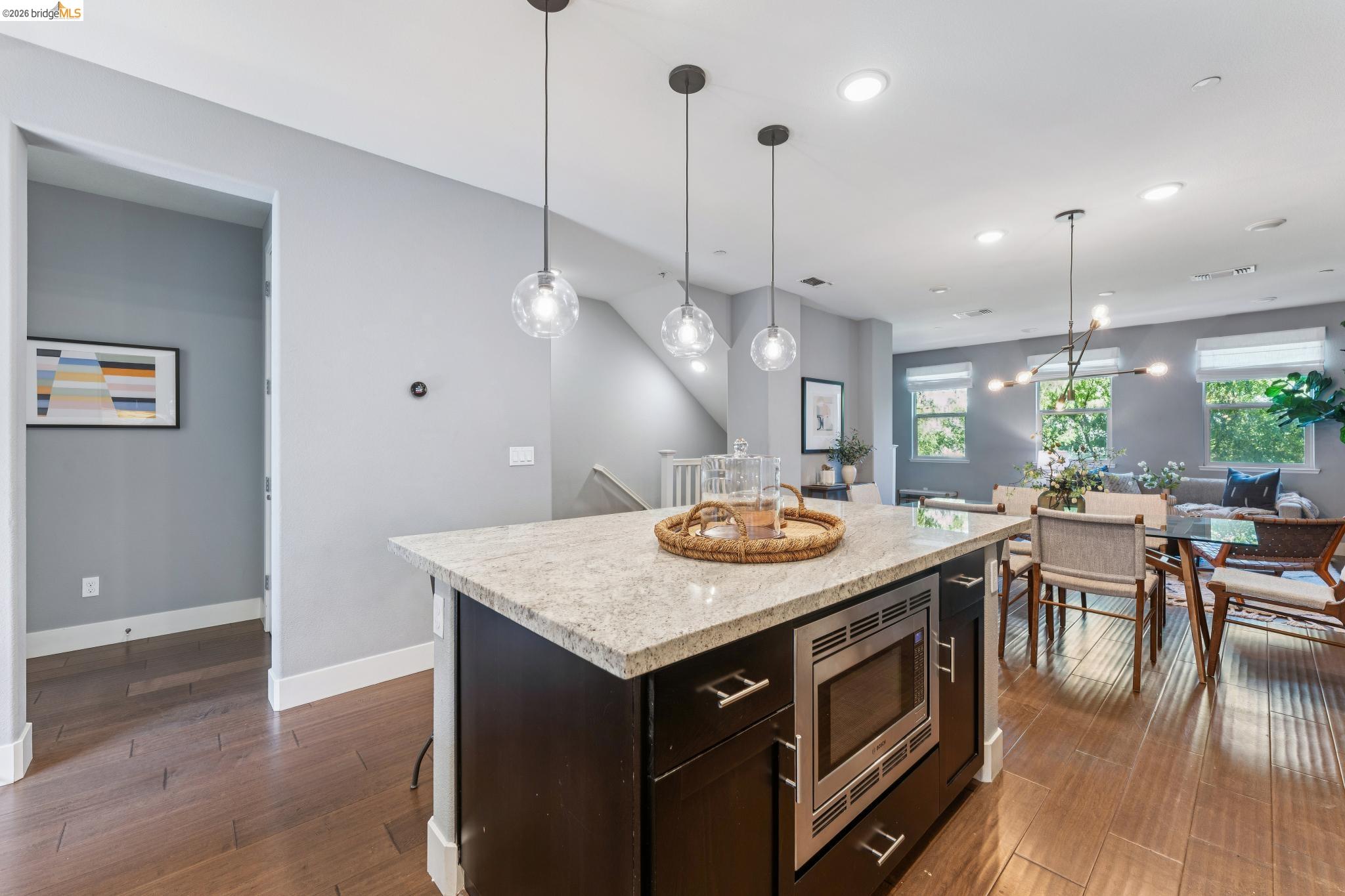 489 Diller Street Alameda, CA 94501 - Photo 60 of 60 Kitchen featuring stainless steel microwave, light stone countertops, dark wood-style floors, open floor plan, and a center island