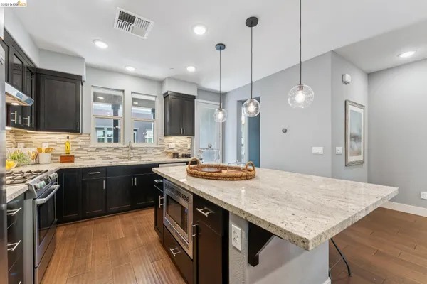 a kitchen with a stove a sink dishwasher a kitchen island with wooden cabinets and floor