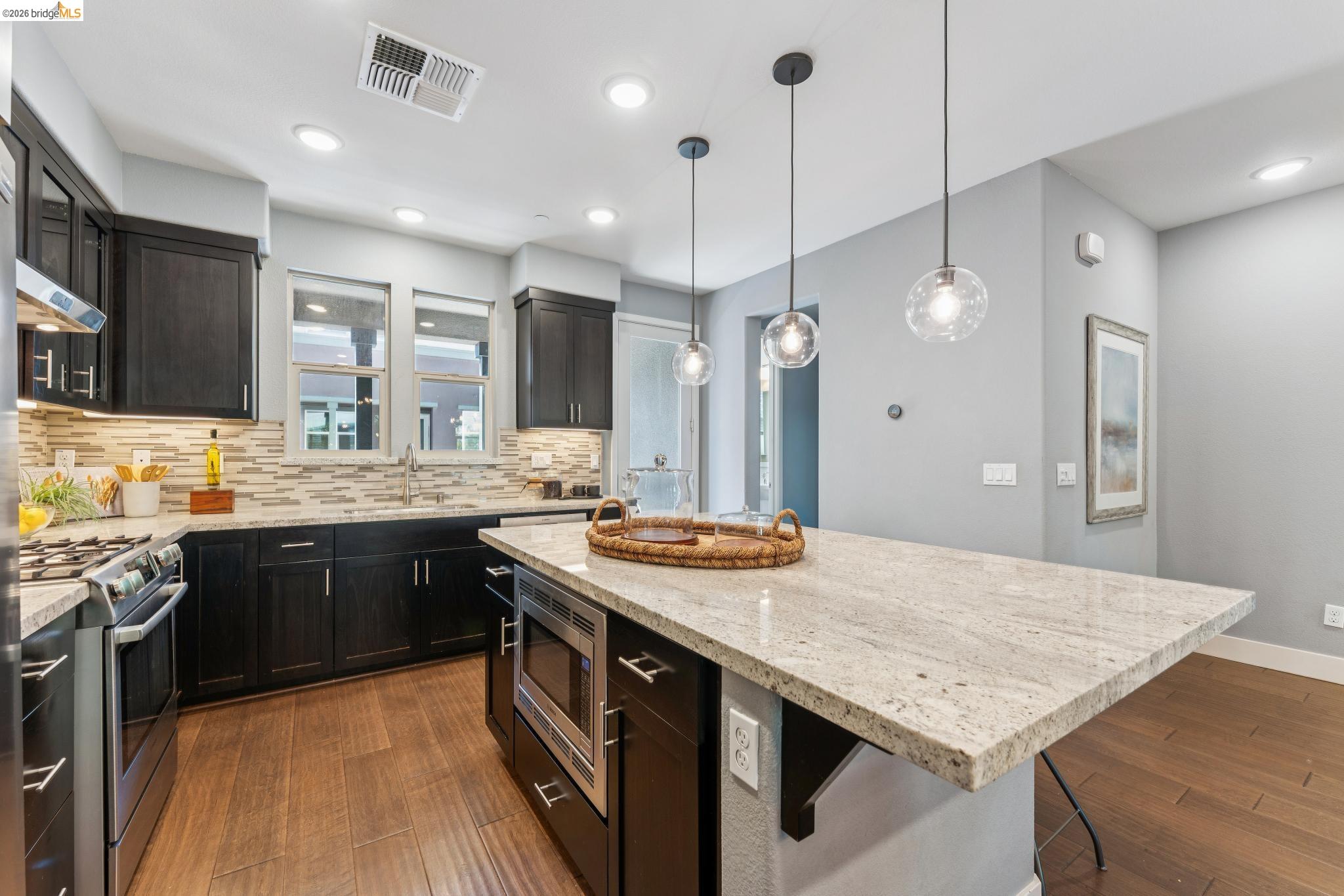 489 Diller Street Alameda, CA 94501 - Photo 3 of 60 Kitchen featuring light stone countertops, dark wood-style flooring, stainless steel appliances, and decorative light fixtures
