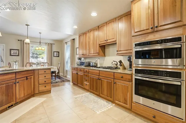 a large kitchen with stainless steel appliances wooden cabinets and a stove top oven