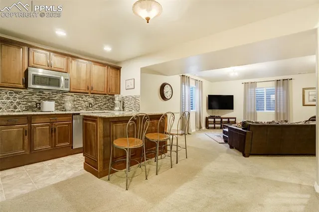 a kitchen with stainless steel appliances granite countertop a stove top oven a sink dishwasher a dining table and chairs with wooden floor