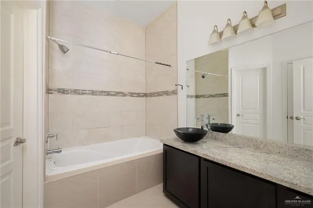a bathroom with a granite countertop sink a mirror and a bathtub
