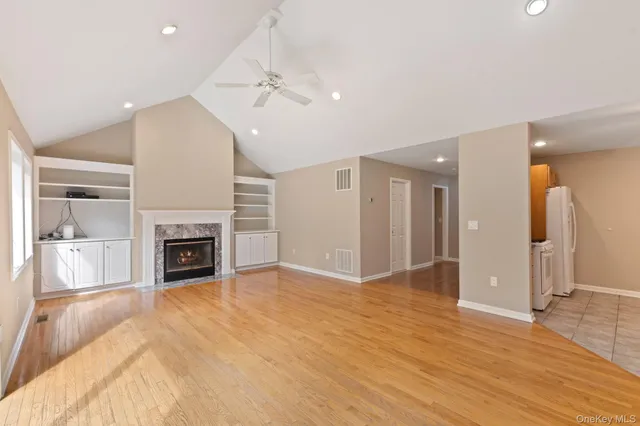 an empty room with wooden floor fireplace and windows