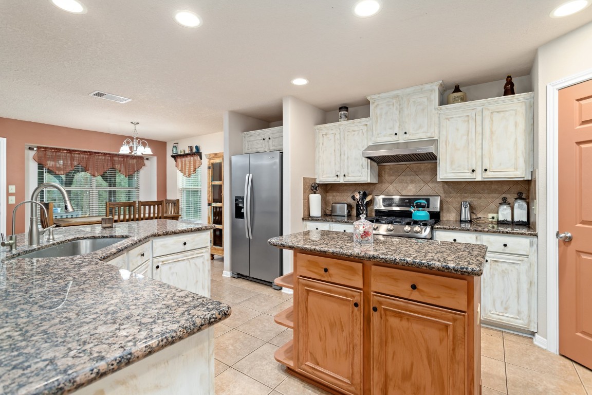 4985 Fm 2827 Road Warren, TX 77664 - Photo 14 of 41 a kitchen with stainless steel appliances granite countertop a stove top oven a sink a refrigerator and white cabinets