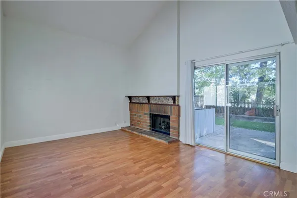 a view of empty room with kitchen and fireplace