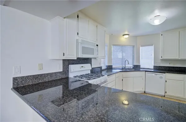 a kitchen with granite countertop white cabinets and white appliances