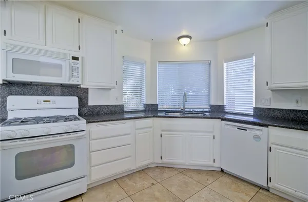 a kitchen with granite countertop white cabinets sink and stainless steel appliances