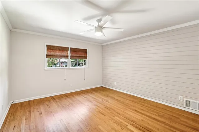 an empty room with wooden floor chandelier fan and windows