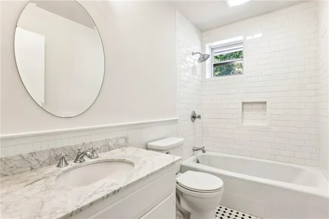 a bathroom with a granite countertop toilet a sink and a mirror