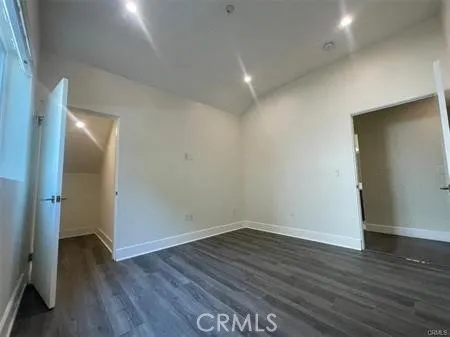 a view of an empty room with wooden floor and closet