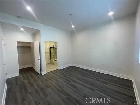 a view of an empty room with wooden floor and closet