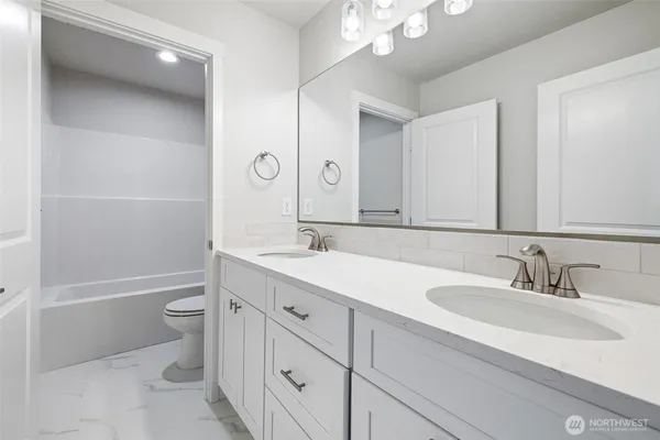 a bathroom with a sink a toilet and a large mirror
