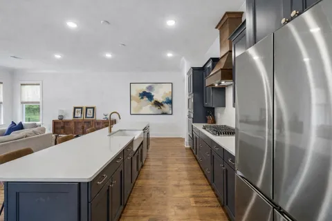 a kitchen with stainless steel appliances a refrigerator a stove a sink a dining table and chairs