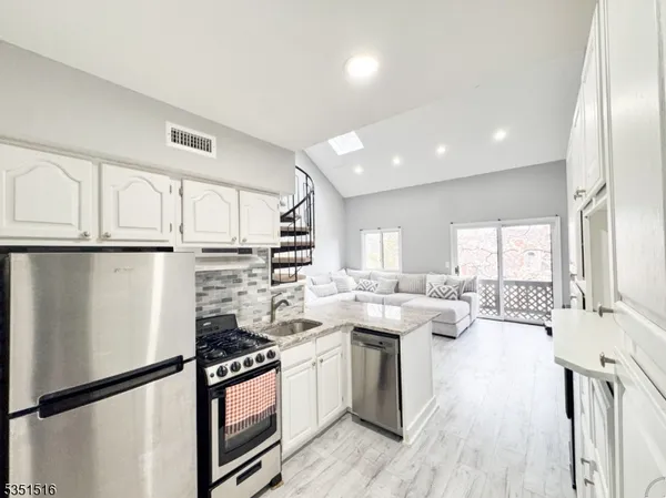 a kitchen with stainless steel appliances granite countertop a lot of counter space and wooden floors
