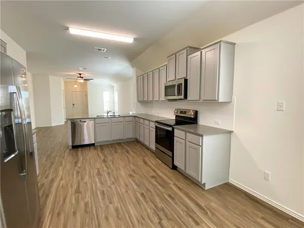 a kitchen with stainless steel appliances granite countertop a stove a sink and a microwave
