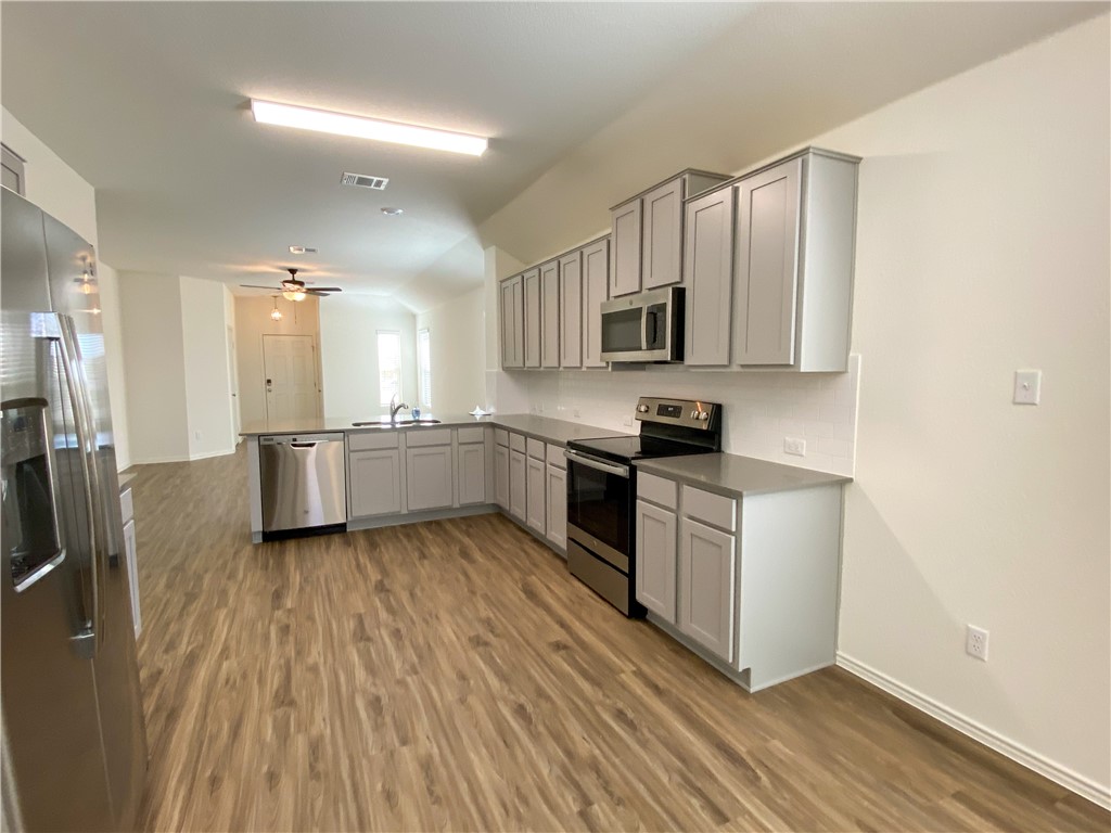 301 Greatest Gift Way Jarrell, TX 76537 - Photo 8 of 20 a kitchen with stainless steel appliances granite countertop a stove a sink and a microwave