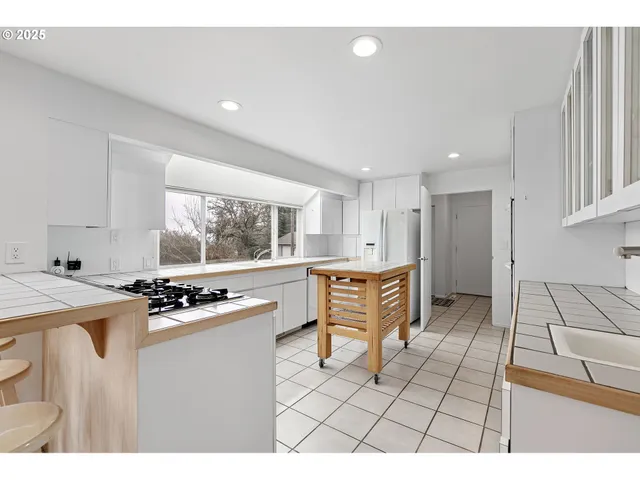 a kitchen with stainless steel appliances a sink a stove a refrigerator cabinets and a window