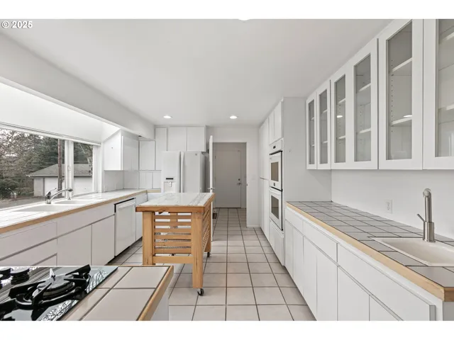 a large white kitchen with stainless steel appliances granite countertop a sink and cabinets