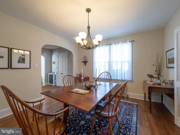 a dining room with wooden floor a chandelier a wooden table and chairs
