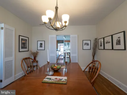 a dining room with wooden floor a chandelier a glass table and chairs