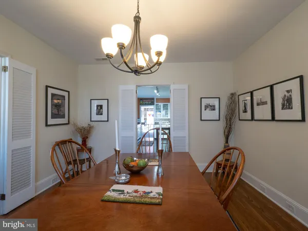 a dining room with wooden floor a chandelier a glass table and chairs