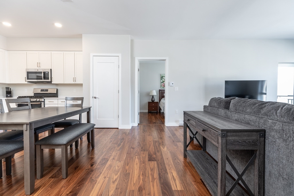 3531 Washington Street, Unit 322D Boston, MA 02130 - Photo 15 of 24 a kitchen with granite countertop a stove top oven a sink dishwasher and a refrigerator with wooden floor