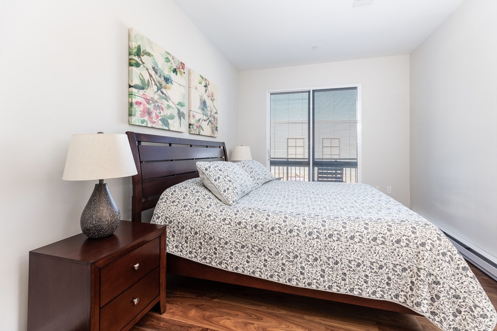 3531 Washington Street, Unit 322D Boston, MA 02130 - Photo 10 of 24 a bedroom with a bed and a lamp on dresser