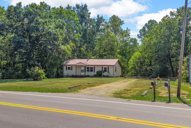 a view of a house with a big yard and large trees