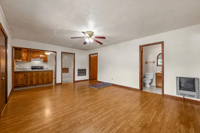 a view of an empty room with a window and wooden floor