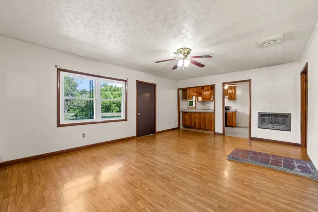 a view of an empty room with a window and wooden floor