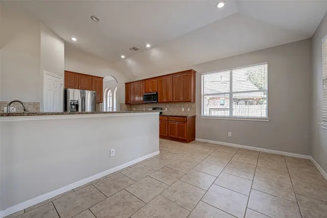 a kitchen with granite countertop a stove top oven a sink dishwasher and a refrigerator with wooden floor