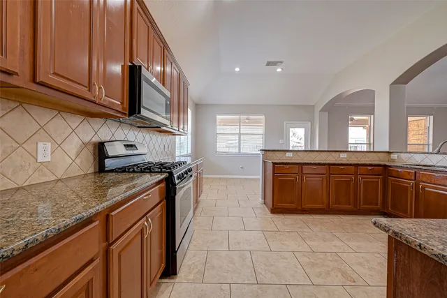 a kitchen with stainless steel appliances granite countertop a stove a sink and a microwave
