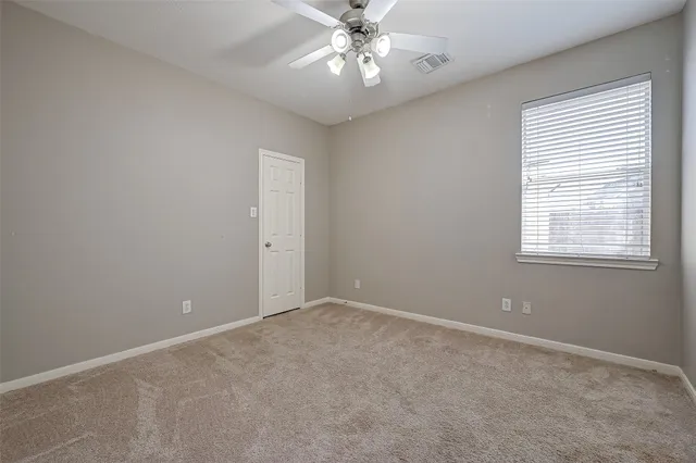 an empty room with a chandelier fan and windows