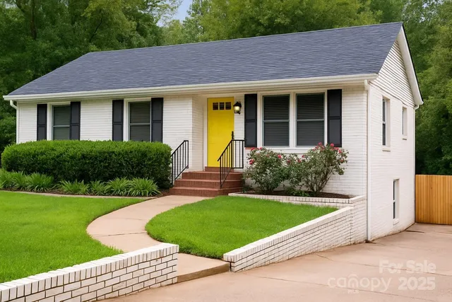 a view of a house with a yard plants and a large tree