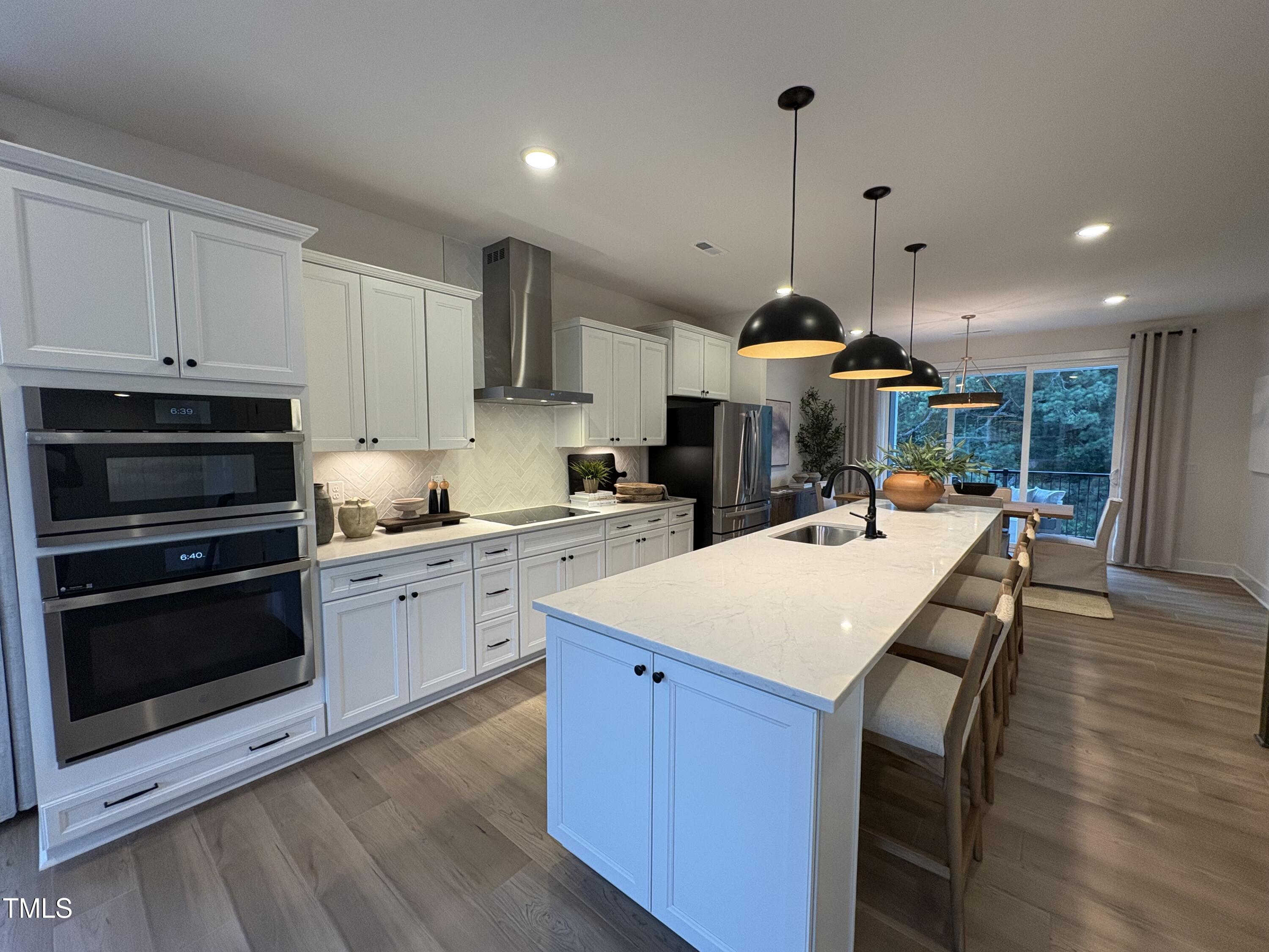 10907 Bayflower Way Raleigh, NC 27617 - Photo 3 of 22 a large kitchen with kitchen island a stove a sink a refrigerator and a fireplace