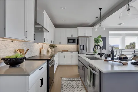 a kitchen with stainless steel appliances a sink a counter top space cabinets and wooden floor