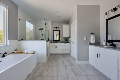 a large white bathroom with a large tub sink vanity and mirror