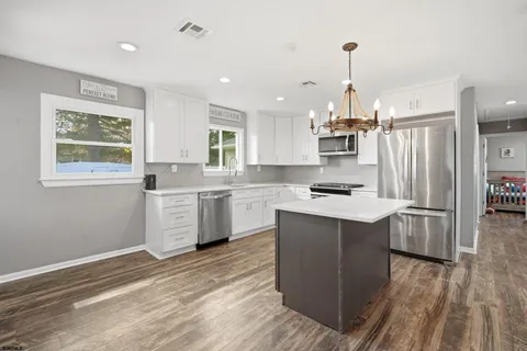 a kitchen with stainless steel appliances a sink a stove a refrigerator and island with wooden floor