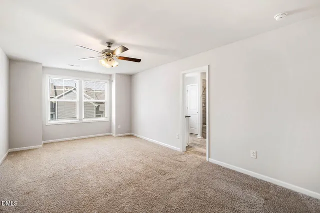 an empty room with windows and chandelier fan