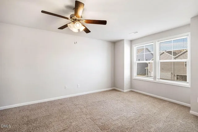 an empty room with a window and a fan