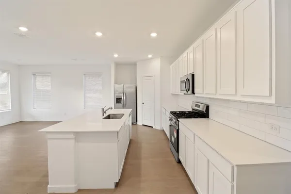 a large white kitchen with stainless steel appliances granite countertop a large counter top and a stove