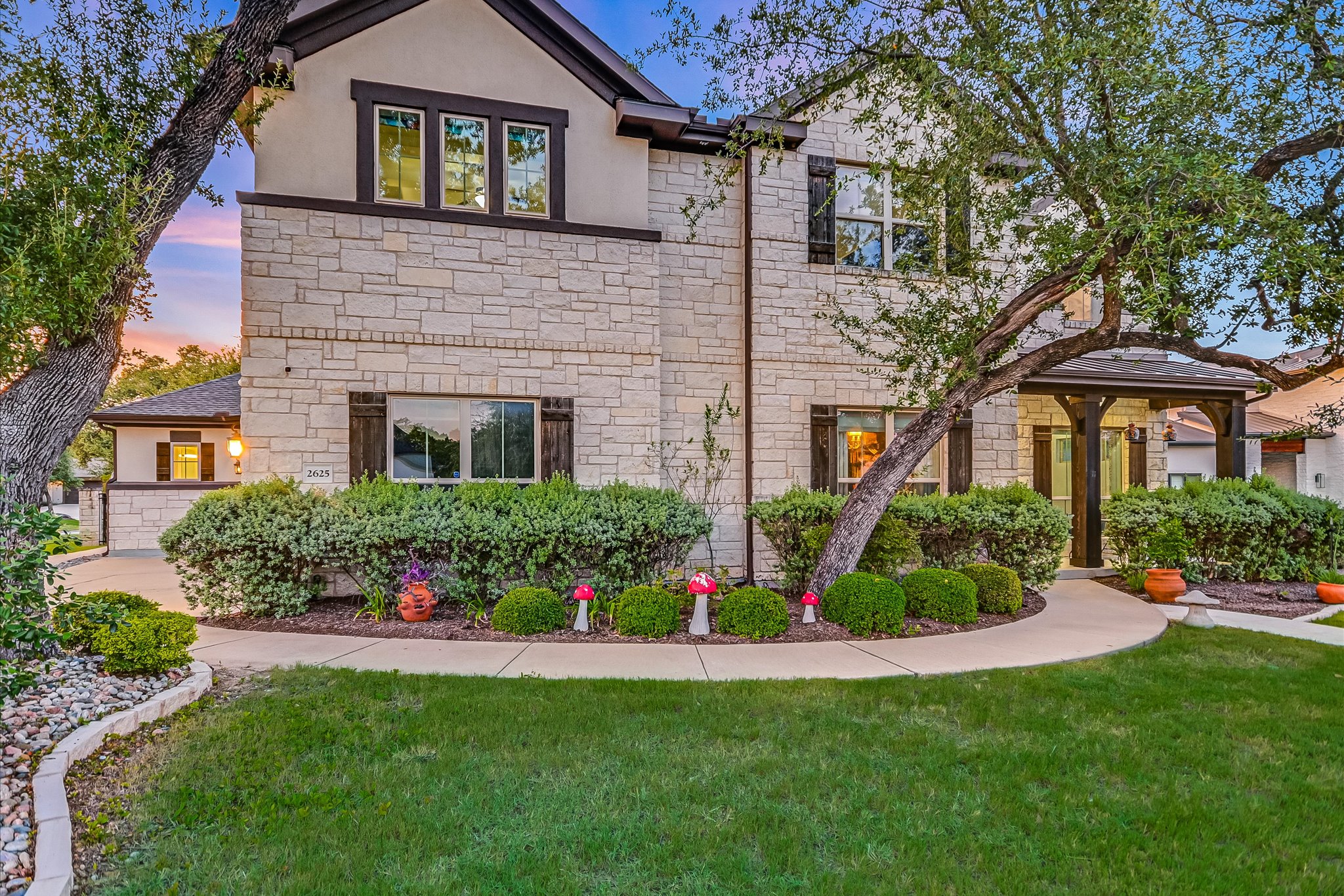 View of front facade featuring stone siding, a front lawn, and stucco siding