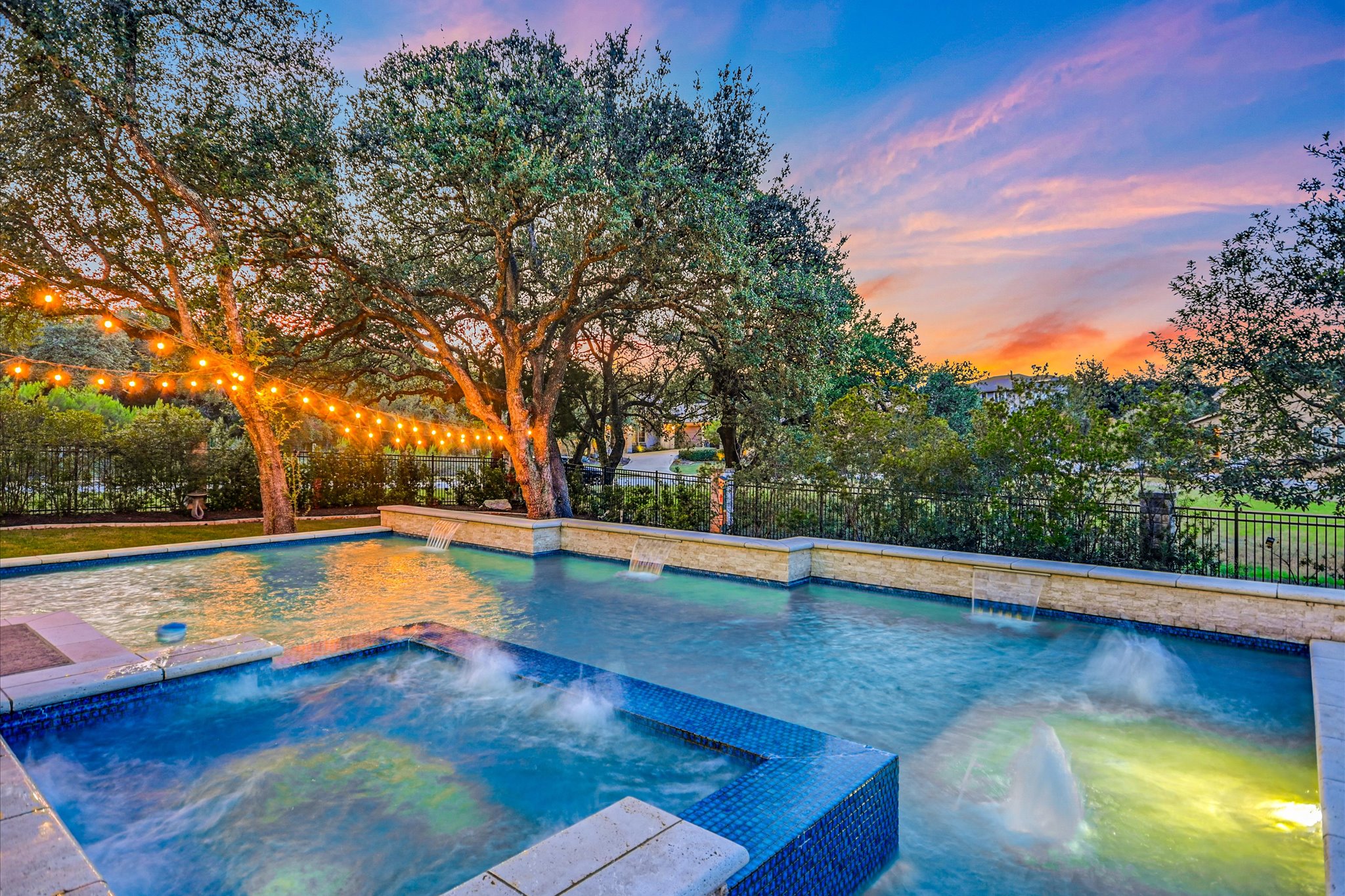 2625 Arion Circle Austin, TX 78730 - Photo 13 of 32 Pool at dusk with a pool with connected hot tub and a fenced backyard