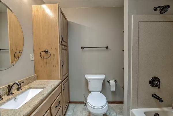 a bathroom with a granite countertop sink toilet and shower