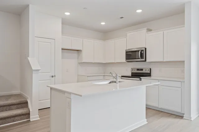 a kitchen with kitchen island a sink stainless steel appliances and white cabinets