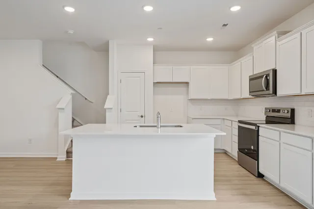 a kitchen with kitchen island white cabinets and stainless steel appliances