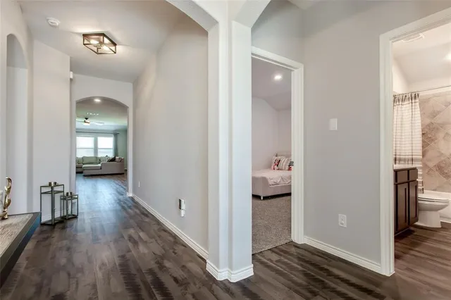 a view of a hallway with wooden floor and a bedroom