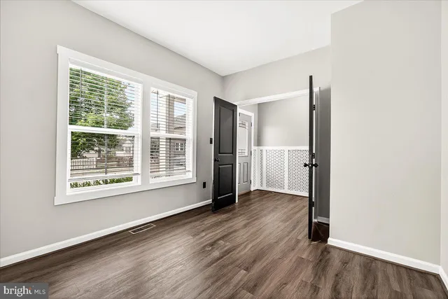 an empty room with wooden floor cabinet and windows