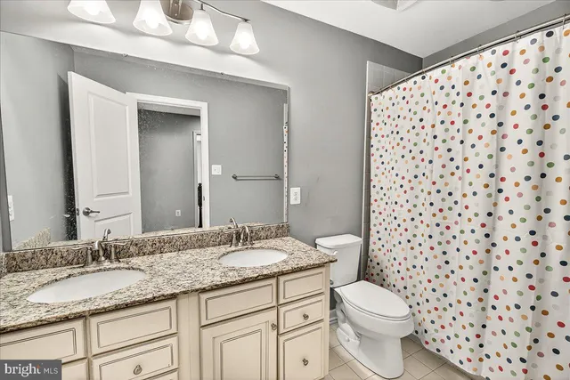 a bathroom with a granite countertop sink a toilet and a mirror