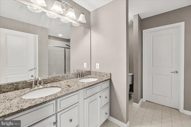 a bathroom with a granite countertop double vanity sink and a mirror